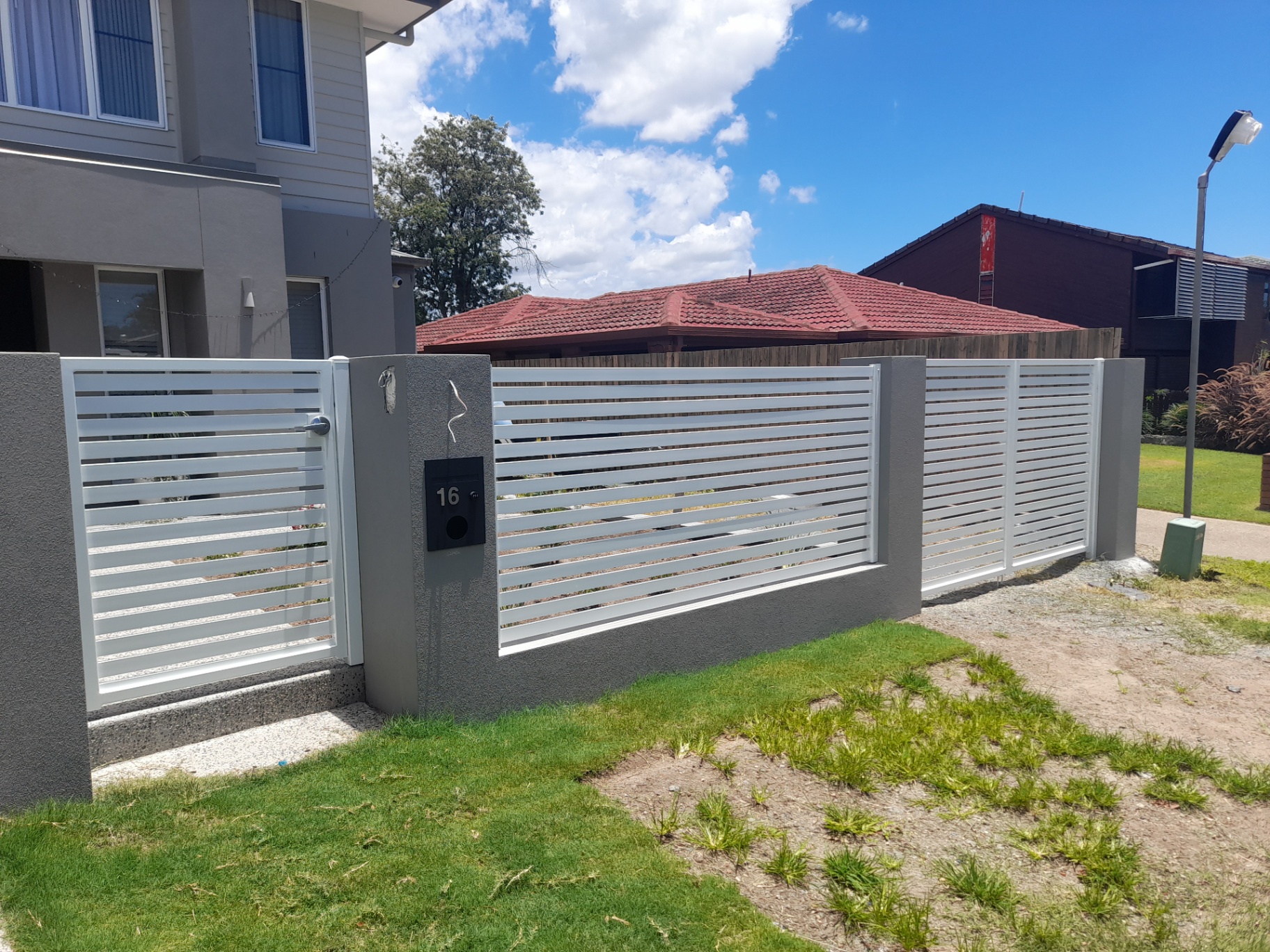 White horizontal slat aluminium driveway gate and matching boundary fence at a Burpengary home - Gateflex, Burpengary