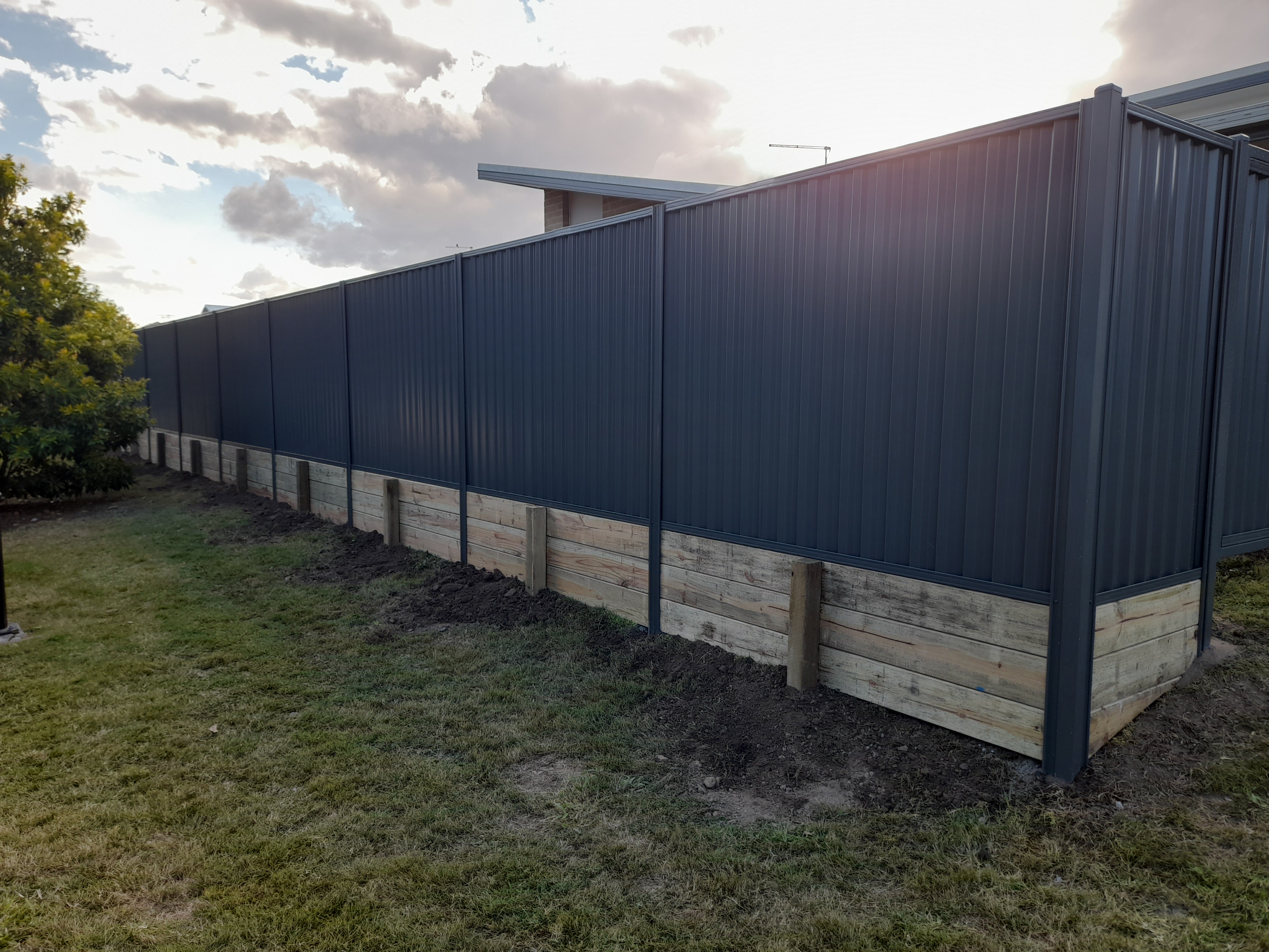 Dark grey Colorbond fence panels installed along a sloped residential boundary - Gateflex, Caboolture