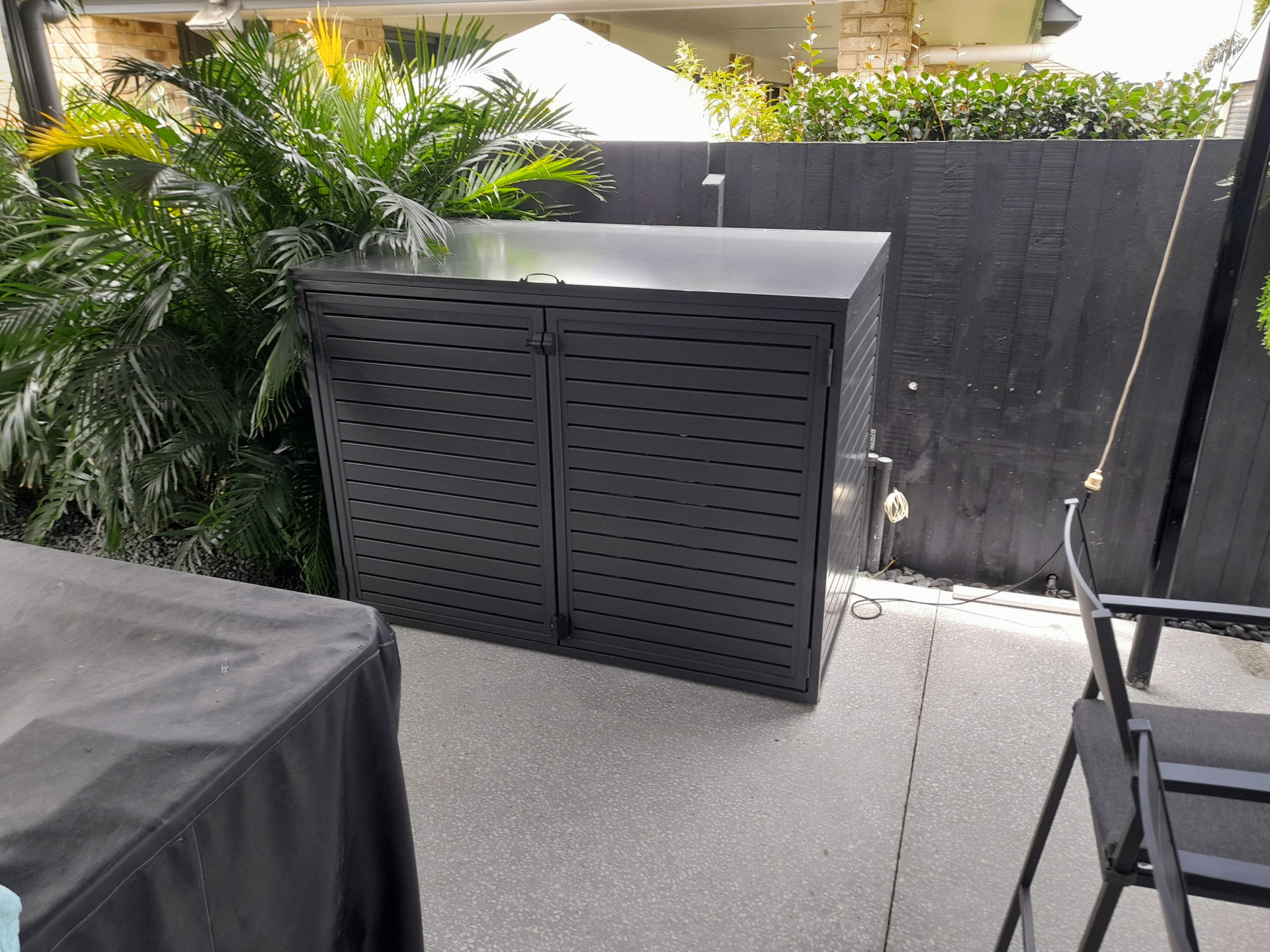 Black aluminium louvre enclosure installed beside tropical landscaping on a residential patio - Gateflex, Caboolture