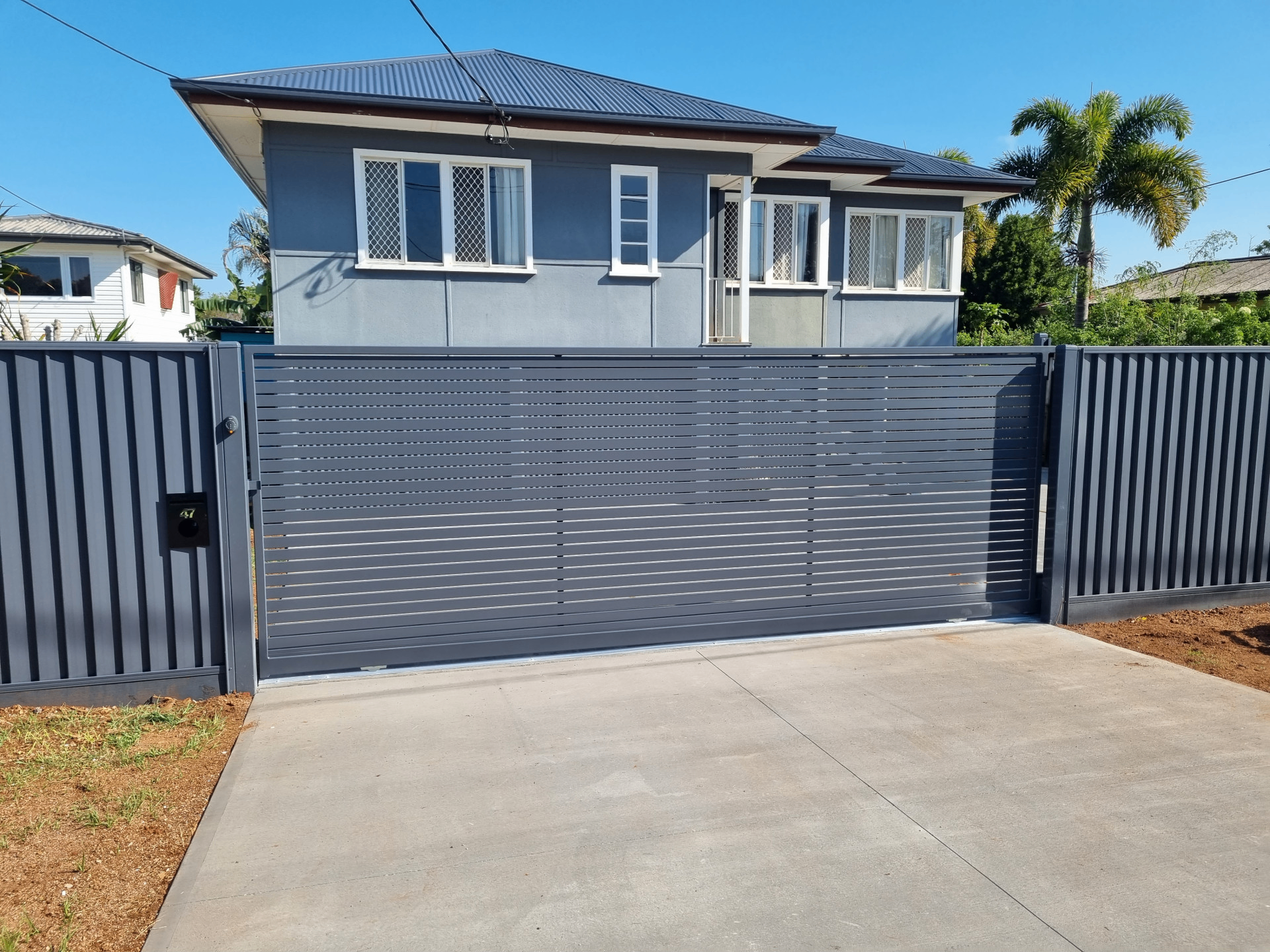 Dark grey horizontal slat aluminium sliding driveway gate across a concrete driveway - Gateflex, Caboolture