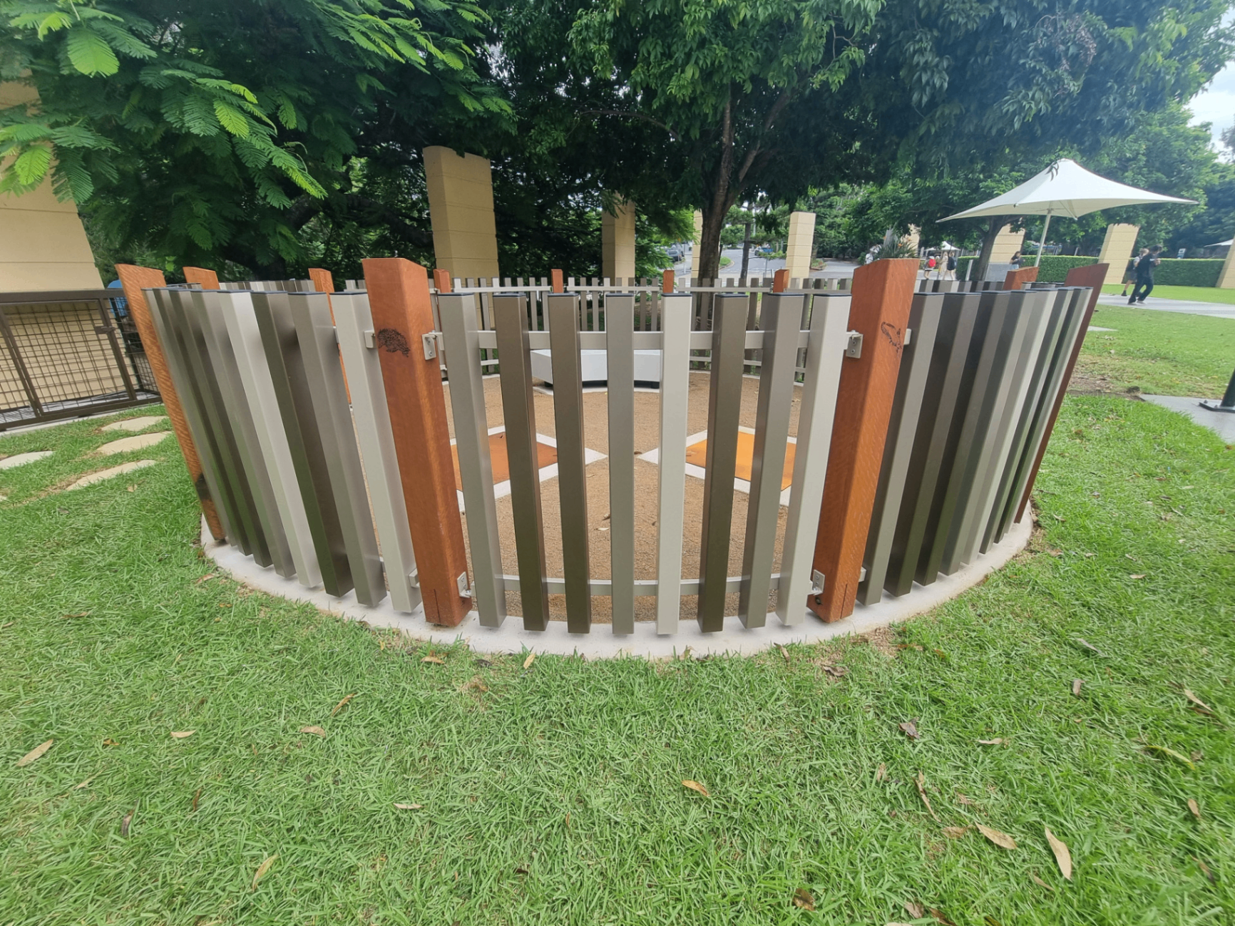 Curved custom aluminium slat fence enclosure with mixed silver and timber-look posts in a parkland setting - Gateflex, Caboolture